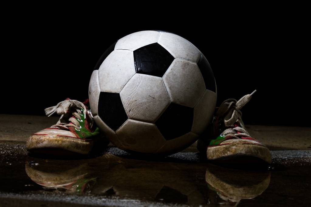 Onvervangbaar verjaardag dennenboom Behang met een voetbal tussen twee sneakers - Fotobehang